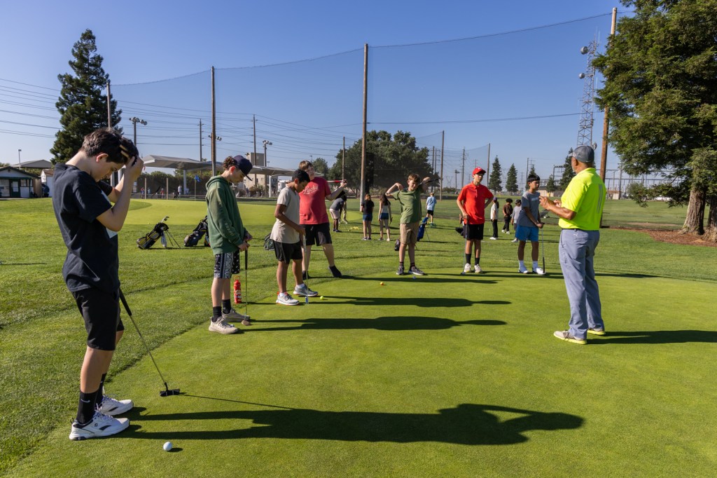 Young golfers listen attentively to the golf instructor.
